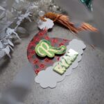 Christmas tag in the shape of a hat witha gold tassle and the name Ryan on it.