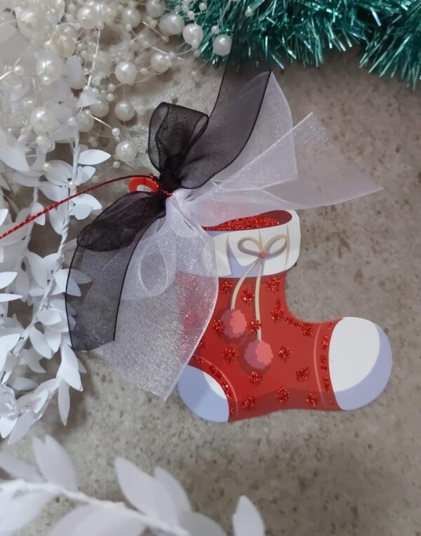 A christmas stocking shaped Christmas tag with a white and black organza ribbon tied to it.